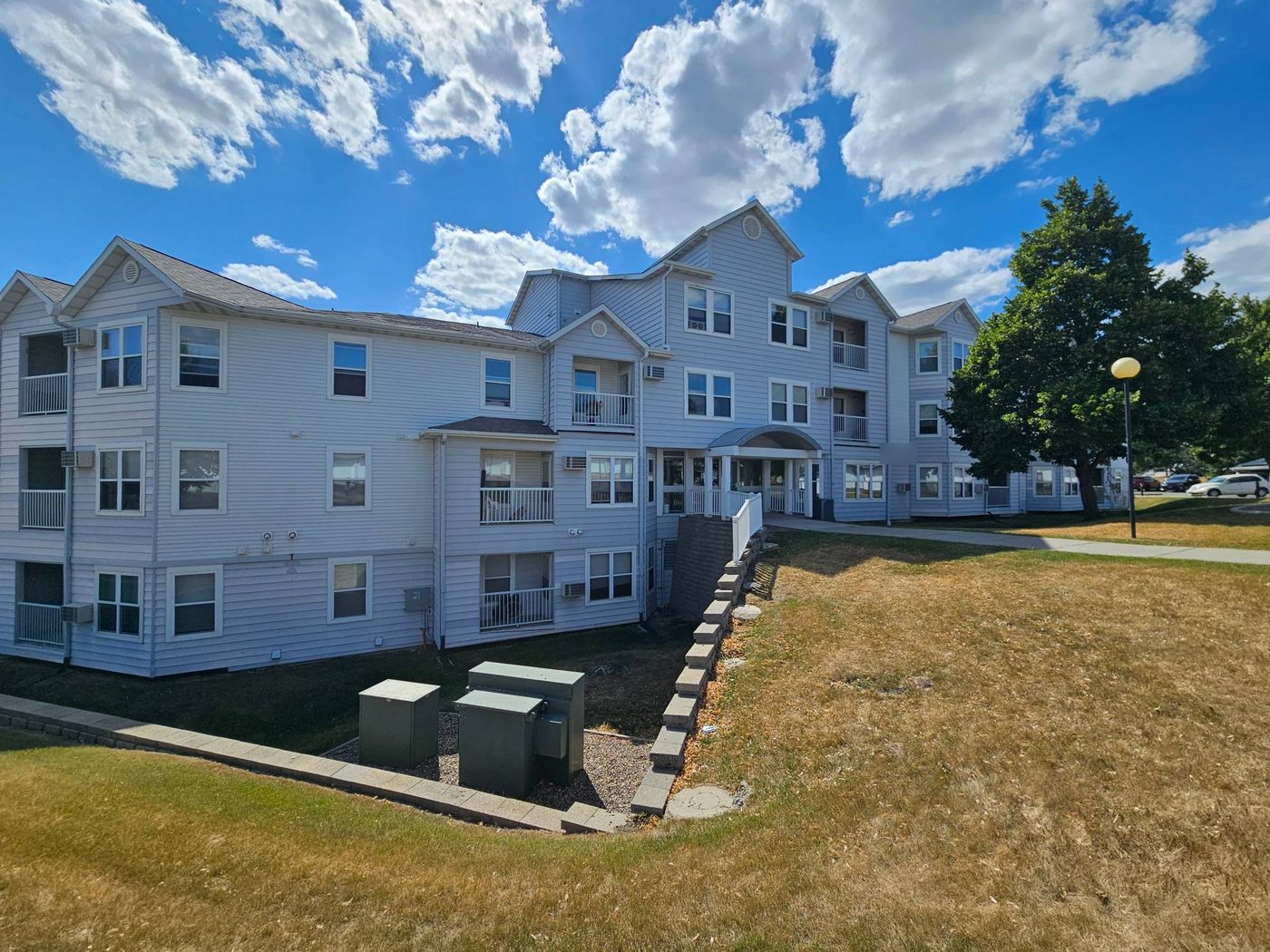 Three-story multifamily building with asphalt shingle roofs under a Colorado sky
